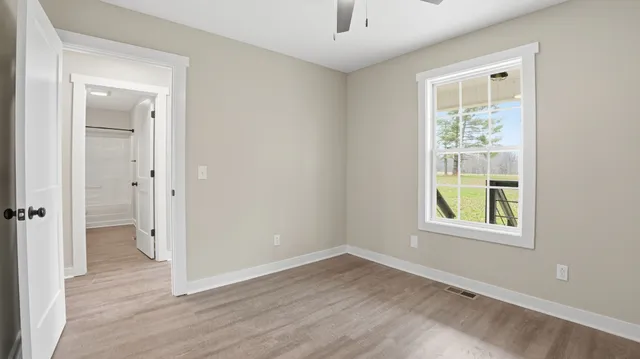 an empty room with wooden floor and windows