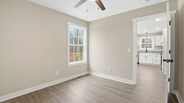 a kitchen with stainless steel appliances granite countertop a refrigerator a sink dishwasher a oven with white cabinets and wooden floor