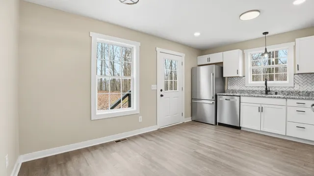 a kitchen with stainless steel appliances granite countertop a refrigerator a sink a stove and white cabinets