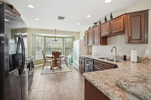 a kitchen with stainless steel appliances granite countertop sink stove refrigerator and cabinets
