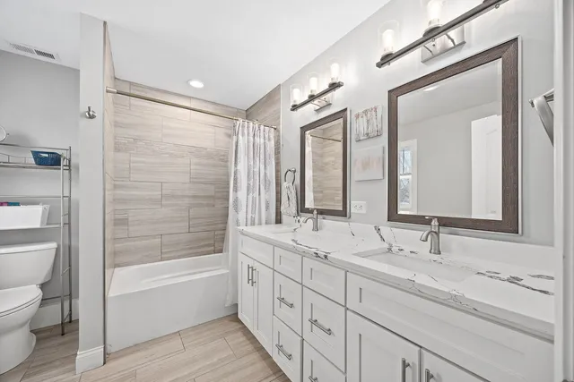 a bathroom with double vanity sink a mirror and a bathtub