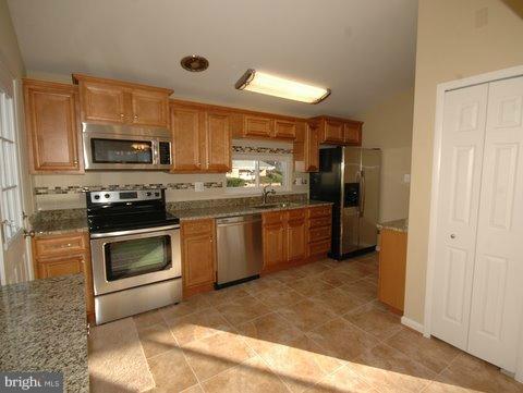 7405 Kathydale Road Pikesville, MD 21208 - Photo 11 of 29 a kitchen with stainless steel appliances granite countertop a stove a sink and a refrigerator