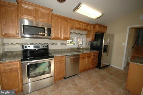 7405 Kathydale Road Pikesville, MD 21208 - Photo 12 of 29 a kitchen with stainless steel appliances a stove a sink a microwave a refrigerator and cabinets