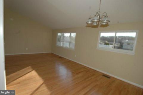 7405 Kathydale Road Pikesville, MD 21208 - Photo 6 of 29 en empty room with wooden floor and chandelier