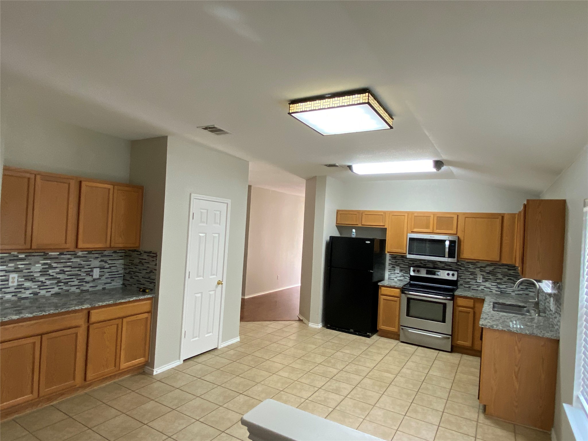 229 Killian Loop Hutto, TX 78634 - Photo 7 of 28 a kitchen with stainless steel appliances kitchen island granite countertop a refrigerator and cabinets