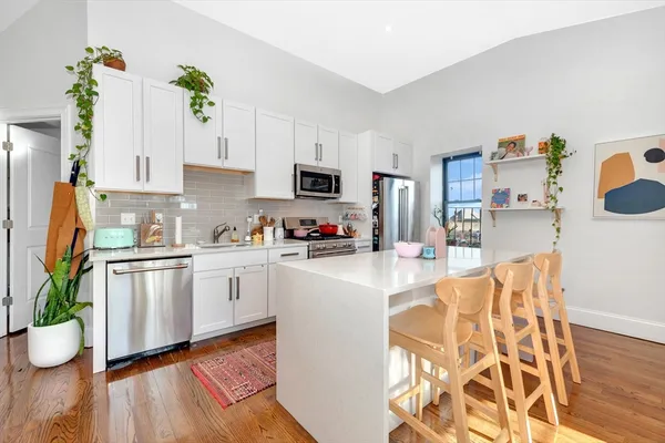 a kitchen with granite countertop a stove a sink and a white cabinets
