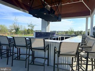 132 Wheelhouse Way, Unit 11 Chester, MD 21619 - Photo 65 of 77 a view of a patio with table and chairs with wooden floor barbeque oven and outdoor seating