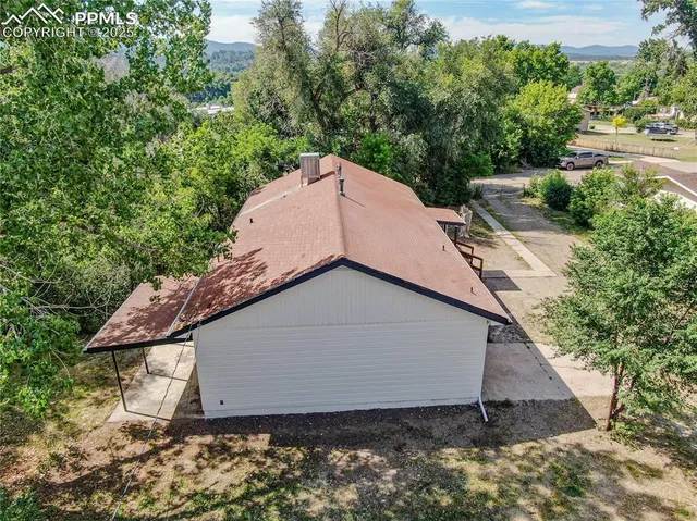 a view of a house with a yard and large trees