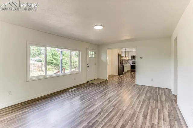 a view of empty room with wooden floor and window