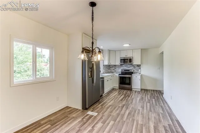 a kitchen with refrigerator a stove and white cabinets