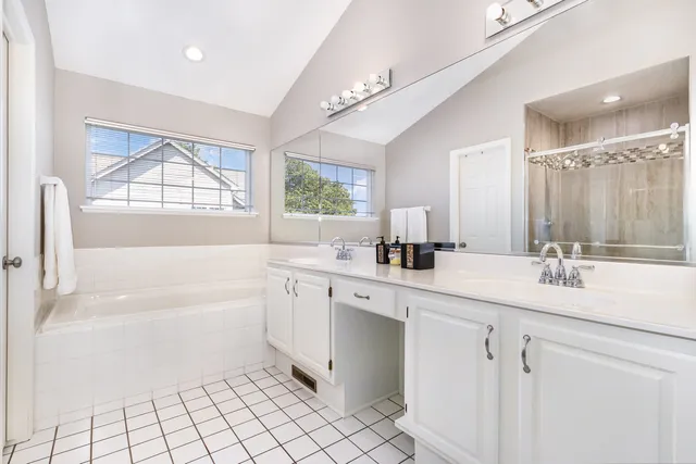 a bathroom with a sink a vanity a mirror a bathtub and next to a window