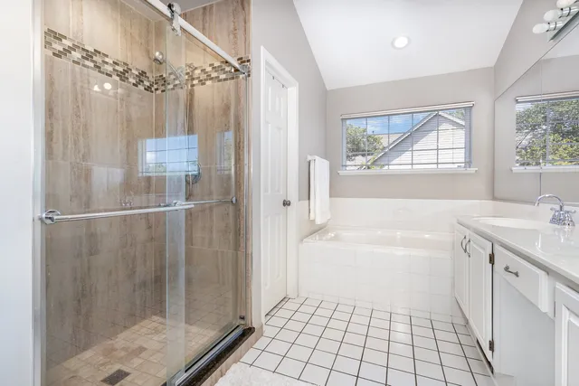 a bathroom with a shower a sink a window and a mirror