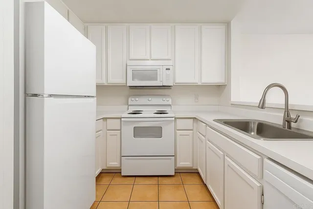 a kitchen with a white stove a sink and a refrigerator with white cabinets