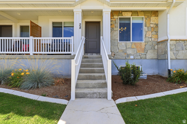 28 East Ginger Gold Road Santaquin, UT 84655 - Photo 8 of 36 Stone veneer facade with a concrete porch, white railings, and a wooden privacy screen