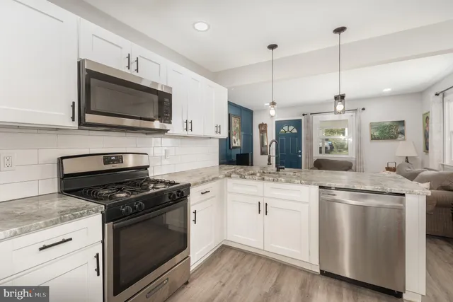 a kitchen with stainless steel appliances granite countertop a stove a sink and a microwave