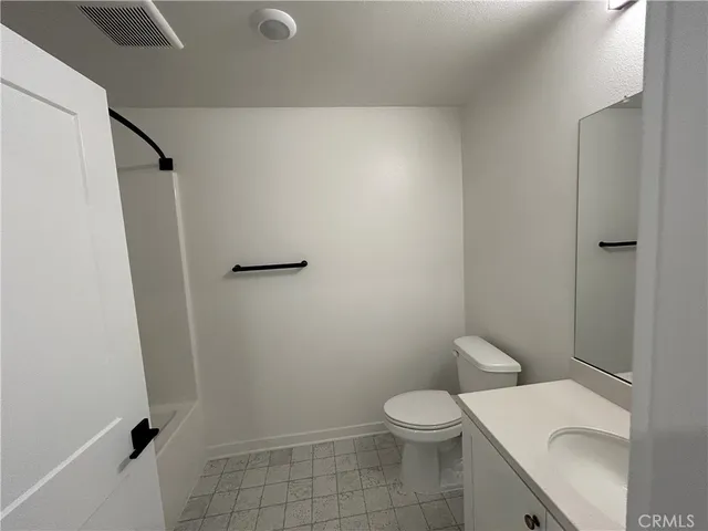 a white toilet sitting next to a white sink and vanity
