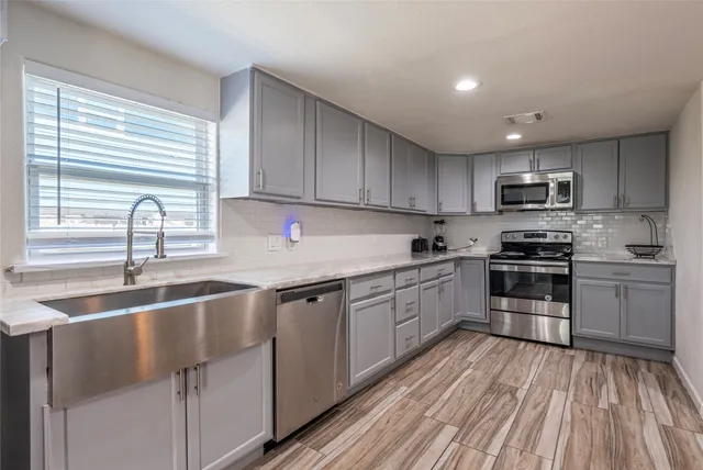 a kitchen with granite countertop a sink stainless steel appliances and window