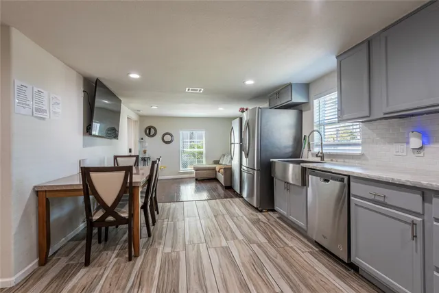 a kitchen with stainless steel appliances a dining table chairs refrigerator and sink