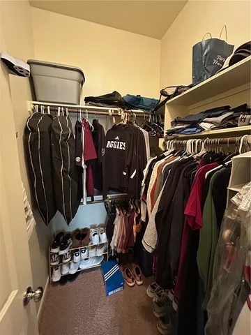 a view of walk in closet with clothes and shoes