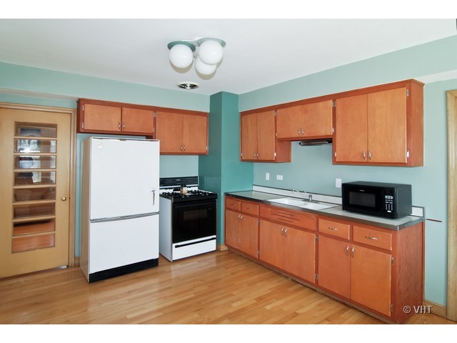 575 Byrd Road Riverside, IL 60546 - Photo 3 of 9 a kitchen with stainless steel appliances granite countertop a refrigerator a sink dishwasher a stove and a microwave oven on the blue kitchen countertops with wooden floor