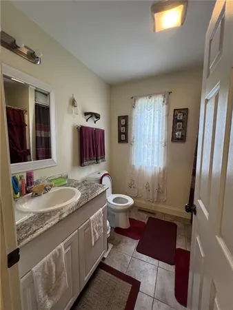 a bathroom with a granite countertop toilet sink and mirror