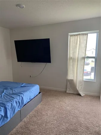 a bedroom with a bed and a flat tv screen on dresser