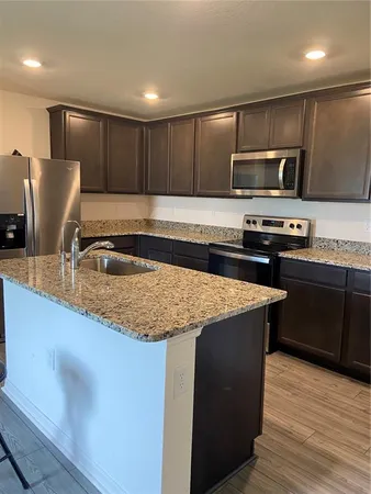 a kitchen with stainless steel appliances granite countertop a sink a stove a microwave and wooden cabinets