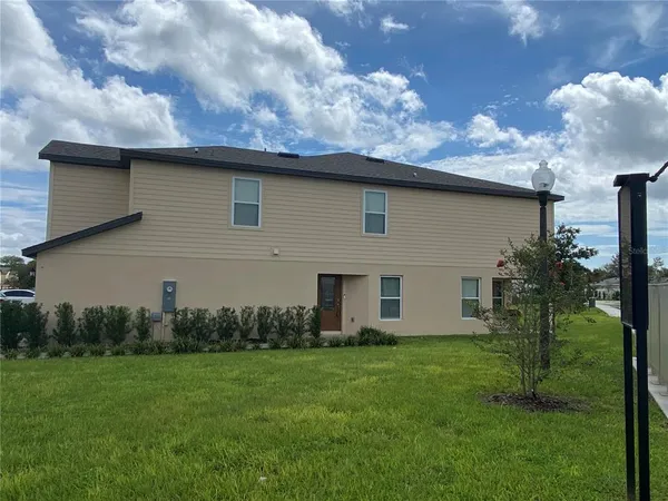 a brick house with a yard and a large tree