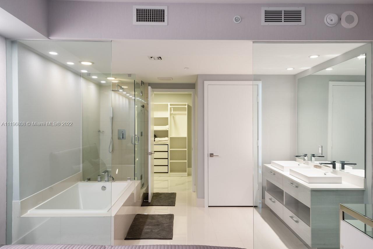 a bathroom with a double vanity sink a large mirror and a bathtub
