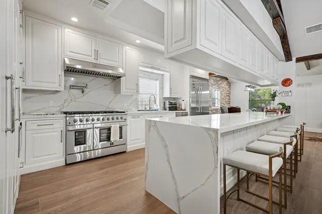 a kitchen with stainless steel appliances white cabinets and wooden floor