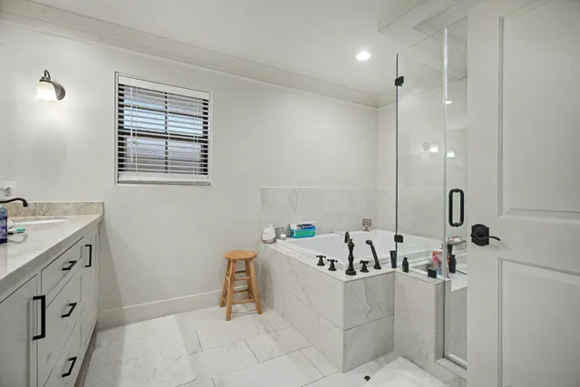a bath room with a sink vanity tub and shower