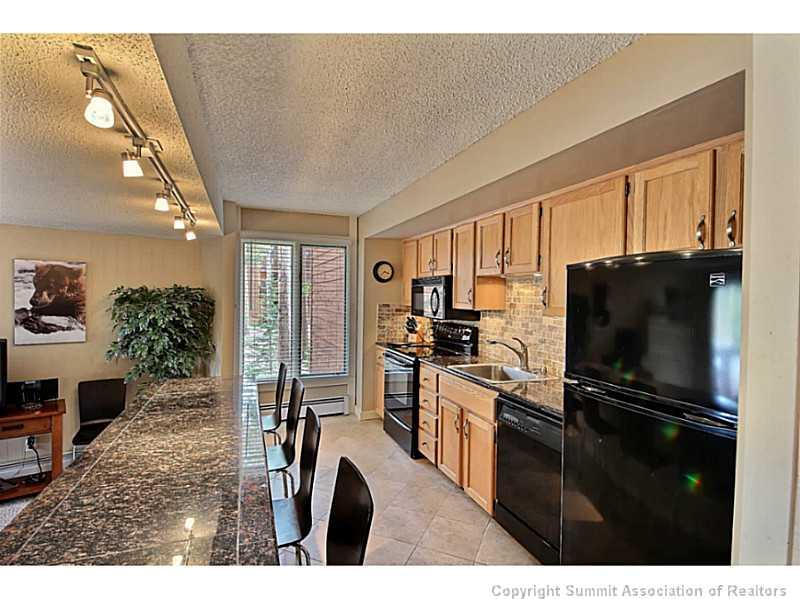 1100 Ski Hill Road, Unit 36 Breckenridge, CO 80424 - Photo 5 of 17 a kitchen with refrigerator a microwave a sink and cabinets