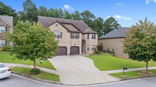 a front view of a house with a garden and trees