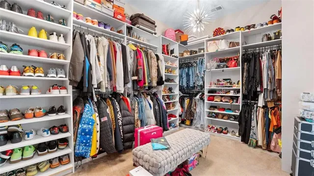 a view of walk in closet with clothes and shoes