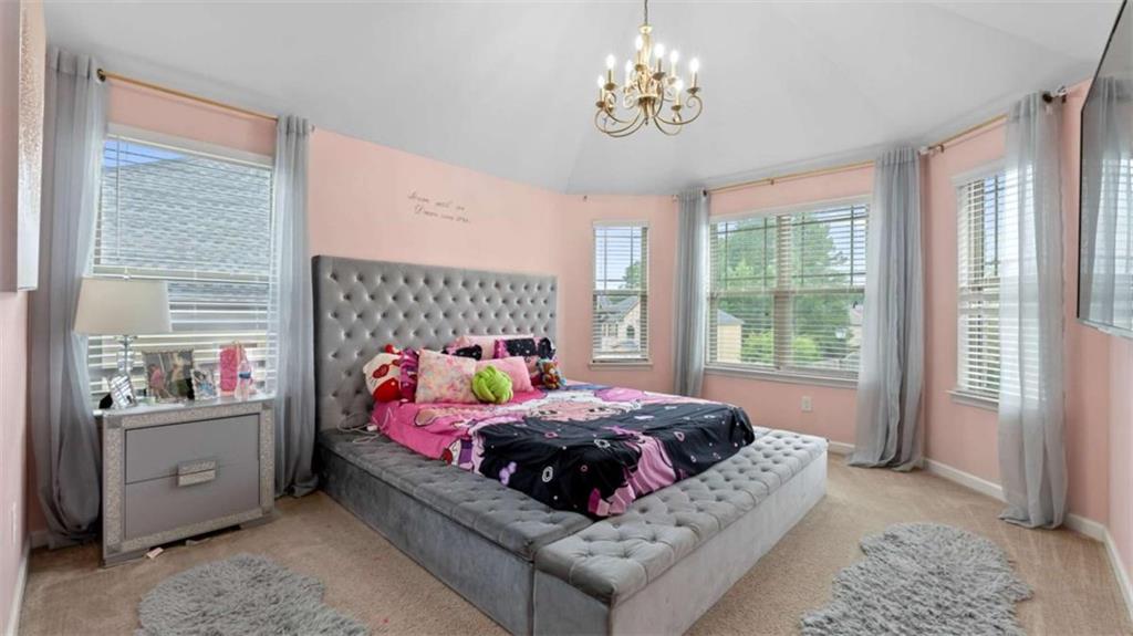 2328 Austin Common Way Dacula, GA 30019 - Photo 40 of 52 a bedroom with a bed chandelier and a window