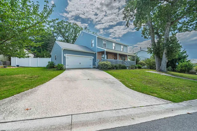 a view of a white house next to a yard with big trees