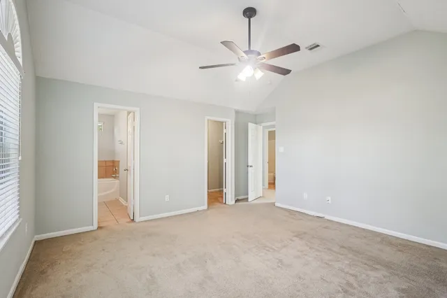 an empty room with chandelier fan and windows