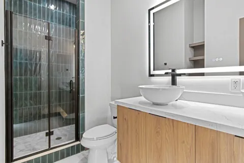 a bathroom with a granite countertop sink a toilet and shower
