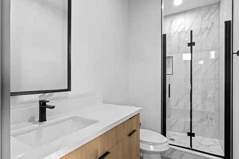 a bathroom with a granite countertop sink toilet and shower