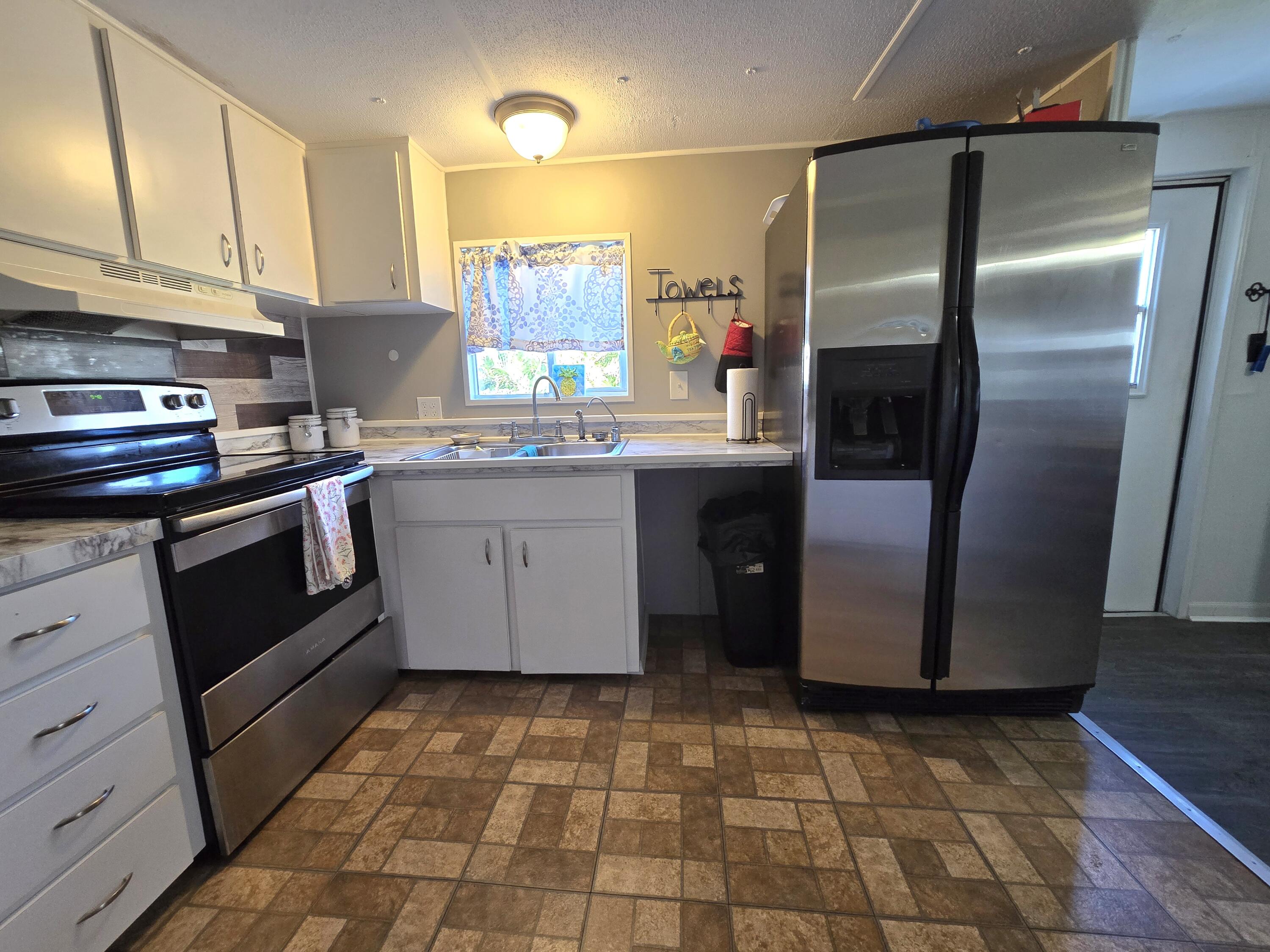 2612 Southeast 29th Street Okeechobee, FL 34974 - Photo 21 of 46 a kitchen with stainless steel appliances granite countertop a stove a sink and a refrigerator