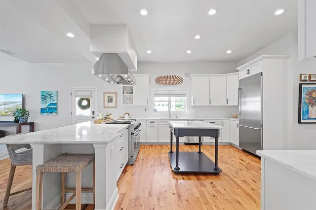 a kitchen with stainless steel appliances granite countertop sink stove and white cabinets with wooden floor