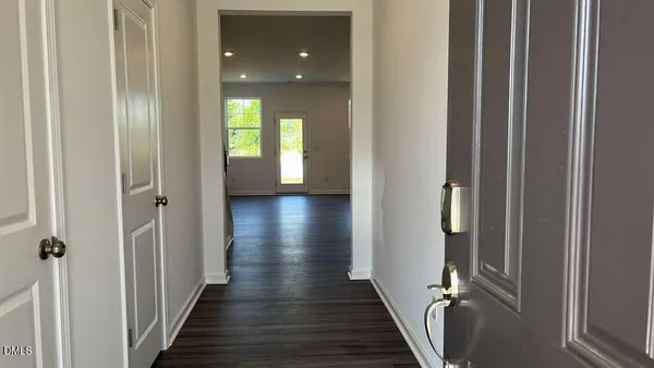 a view of a hallway with wooden floor and a bathroom