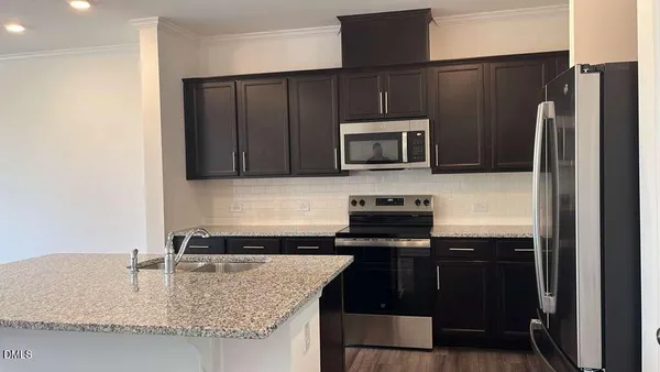 a kitchen with granite countertop a refrigerator stove and microwave