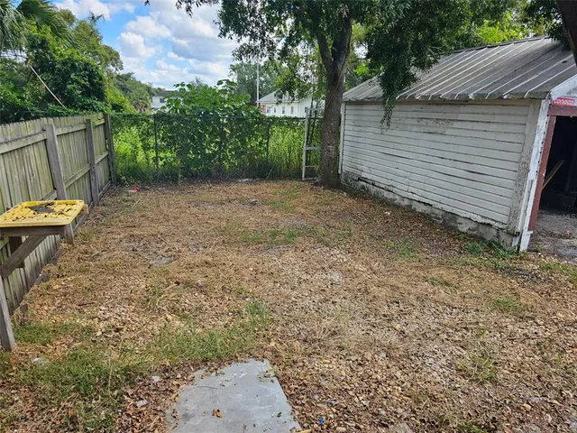 a view of a backyard with large tree and wooden fence