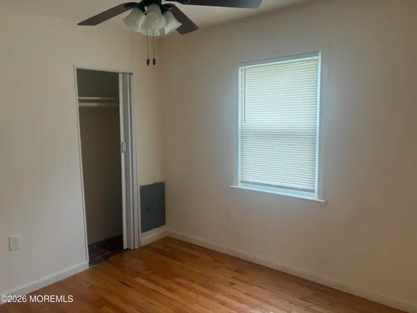 an empty room with a window and a chandelier fan