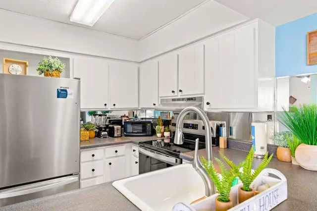 a kitchen with stainless steel appliances kitchen island granite countertop a refrigerator a stove a sink dishwasher and white cabinets with wooden floor