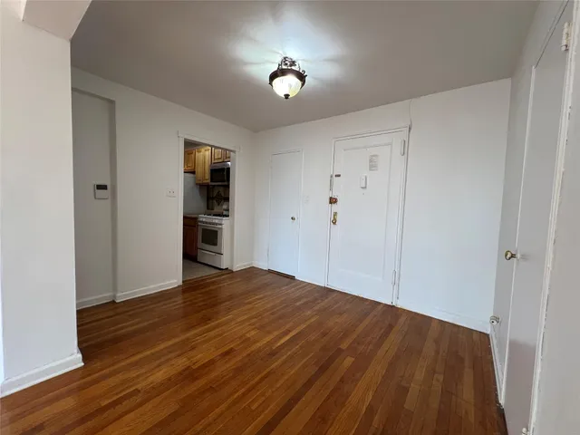 a view of empty room with wooden floor and window