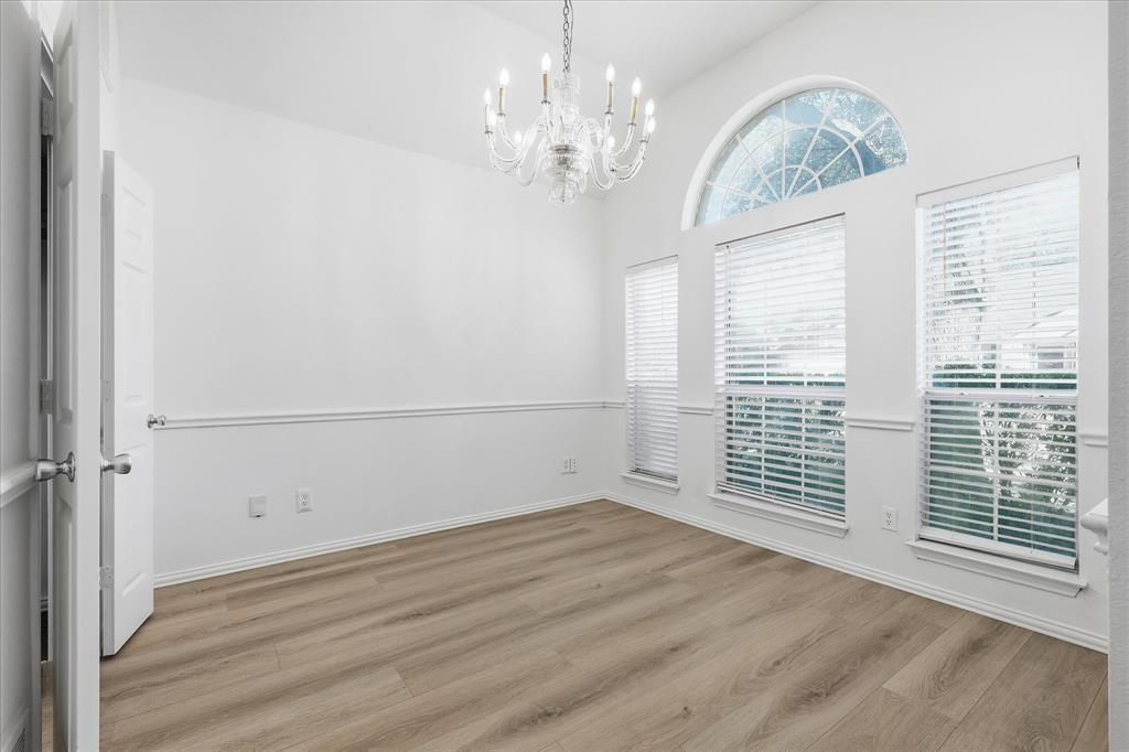 5023 Falcon Hollow Road McKinney, TX 75072 - Photo 7 of 25 Unfurnished room with suspended lighting, light wood-type flooring, and a high ceiling