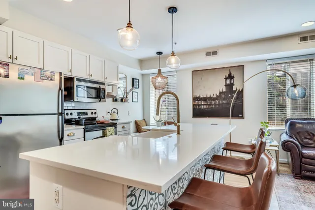 a kitchen with stainless steel appliances granite countertop a stove a refrigerator a kitchen island a dining table and chairs