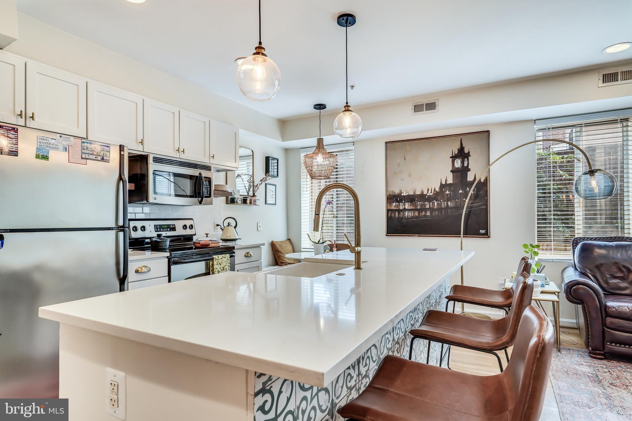 5405 9th Street Northwest, Unit 106 Washington, DC 20011 - Photo 5 of 21 a kitchen with stainless steel appliances granite countertop a stove a refrigerator a kitchen island a dining table and chairs